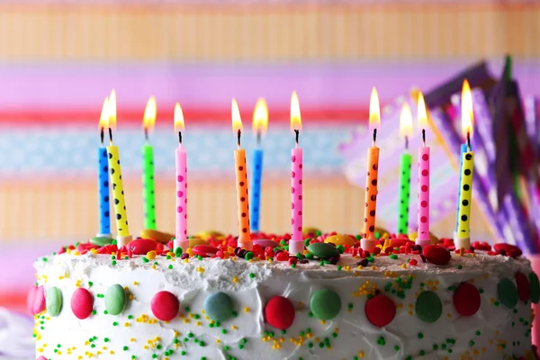 Tarta de cumpleaños con vela sobre fondo a rayas de colores —  Fotos de Stock