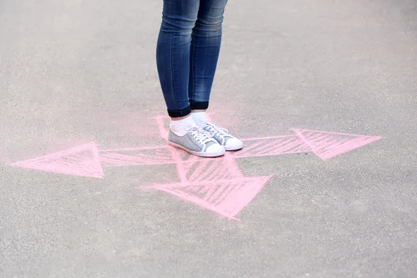 Female feet and drawing arrows on pavement background — Stock Photo, Image