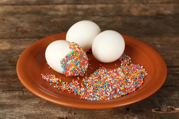 Decorating Easter eggs on color plate on wooden table, closeup — Stock Photo, Image