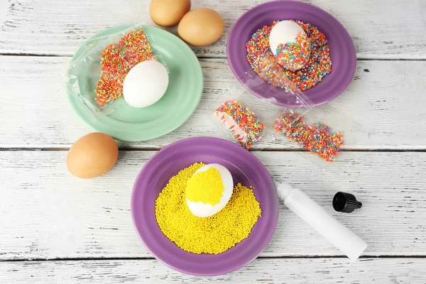 Decorating Easter eggs on color plate on wooden table, closeup — Stock Photo, Image