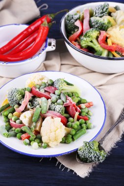 Dondurulmuş sebze peçeteye ahşap masa arka plan üzerinde plaka üzerinde