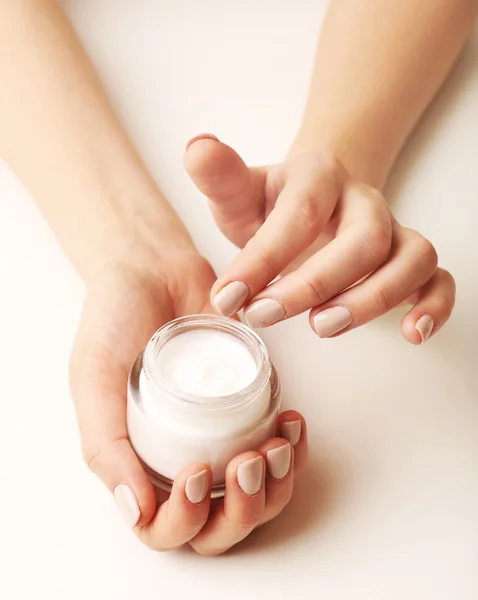 Mãos femininas segurando frasco de creme isolado no branco — Fotografia de Stock