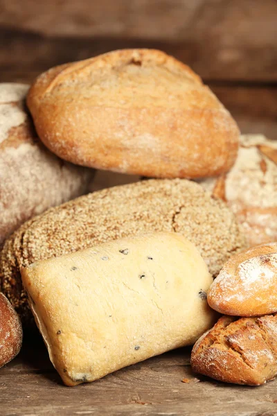 Different fresh bread on old wooden table — Stock Photo, Image