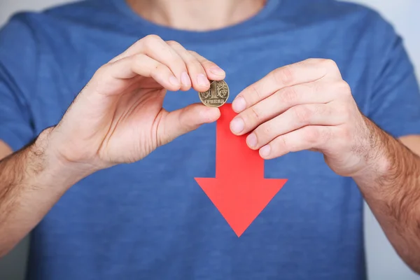 Mannen innehar mynt och röd pil på nära håll — Stockfoto