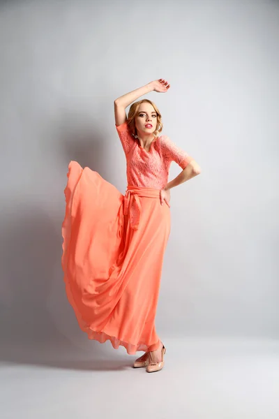 Hermosa mujer joven en vestido de color posando sobre fondo claro —  Fotos de Stock