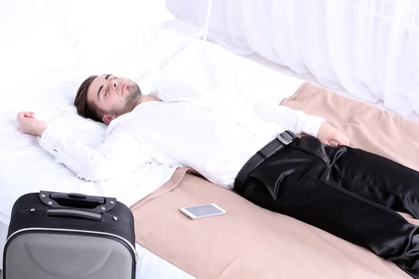 Уставший мужчина отдыхает на кровати в номере — стоковое фото