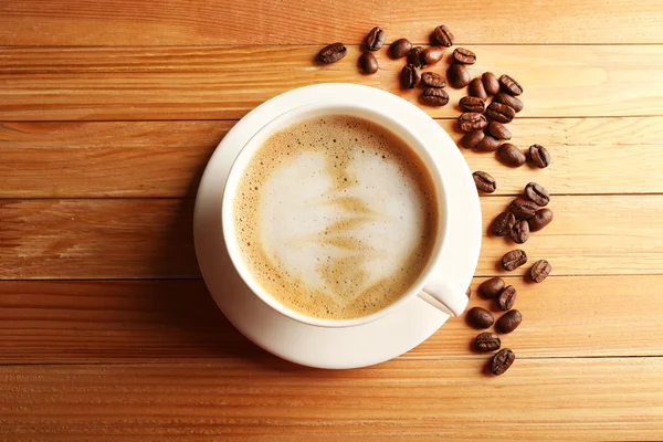 Secangkir kopi latte art dengan biji-bijian di atas meja kayu, pemandangan atas — Stok Foto