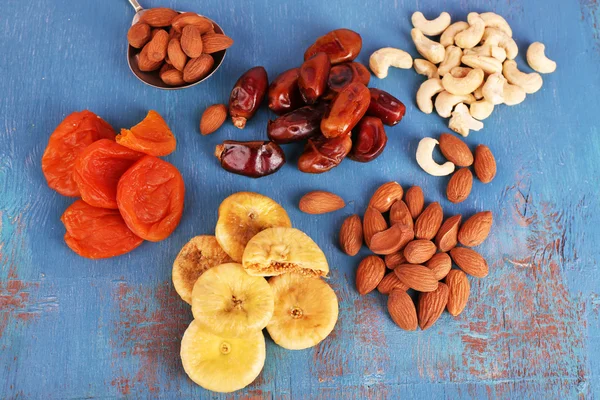 Trockenfrüchte und Nüsse auf farbigem Holzhintergrund — Stockfoto