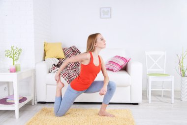 Evde yoga yapan genç bir kadın.