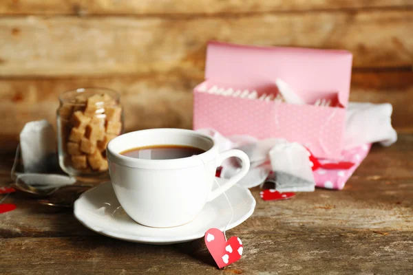 Coração em forma de etiquetas de teca e xícara de chá com no fundo de madeira — Fotografia de Stock