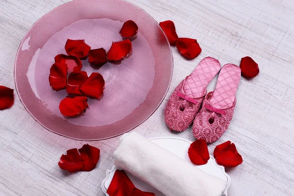 Cuenco spa con agua, pétalos de rosa, toalla y zapatillas sobre fondo claro. Concepto de pedicura o tratamiento de spa natural —  Fotos de Stock