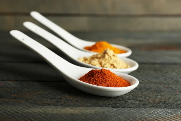 Different kinds of spices in spoons on wooden background — Stock Photo, Image