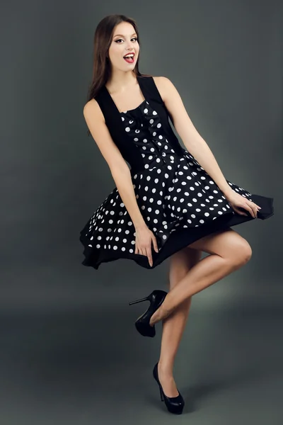 暗い灰色の背景にドット ドレスで美しい若い女性 — ストック写真