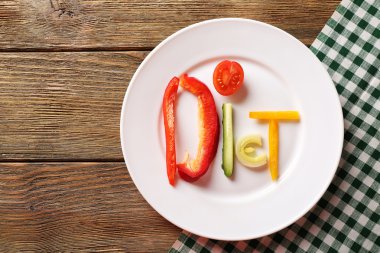 Beyaz ahşap masa, üstten görünüm tabağa dilimlenmiş sebze kelime diyet yapılmış