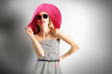 Pembe şapka ile güneş gözlüğü gri arka plan üzerinde etkileyici genç modeli