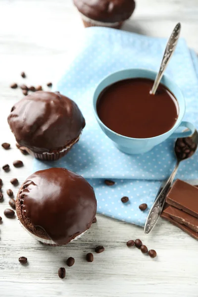 Вкусные домашние шоколадные кексы и чашка кофе на деревянном столе — стоковое фото