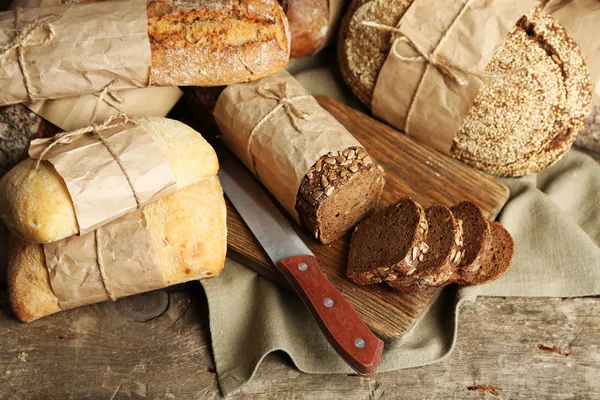 Different fresh bread, on old wooden table — Stock Photo, Image