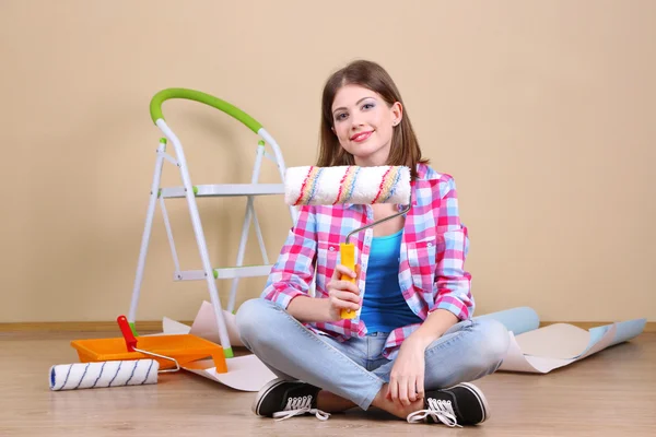 Beautiful girl sitting on floor with equipment for painting wall — Stock Photo, Image