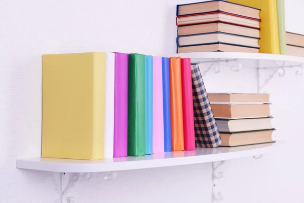 Książki na półkach na tle białej ściany — Zdjęcie stockowe