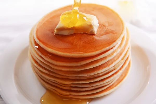 Delicious pancakes with honey on plate on table close-up — Stock Photo, Image