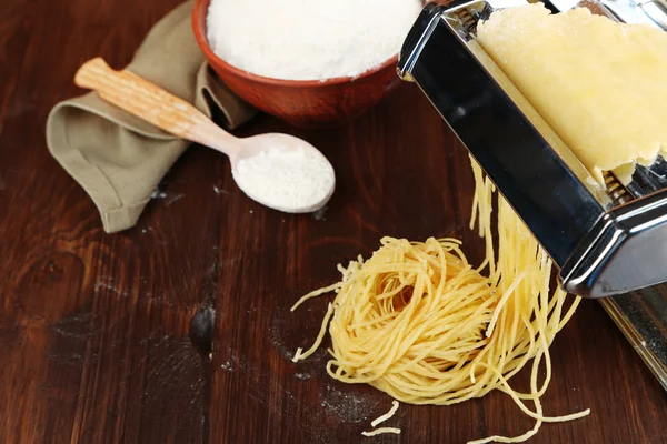 Making vermicelli with pasta machine on wooden background — Stock Photo, Image