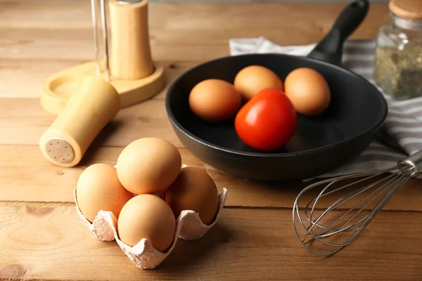 Stilleven met eieren en pan op houten achtergrond — Stockfoto