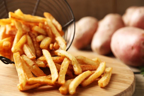 Frites savoureuses dans un panier en métal sur fond de table en bois — Photo