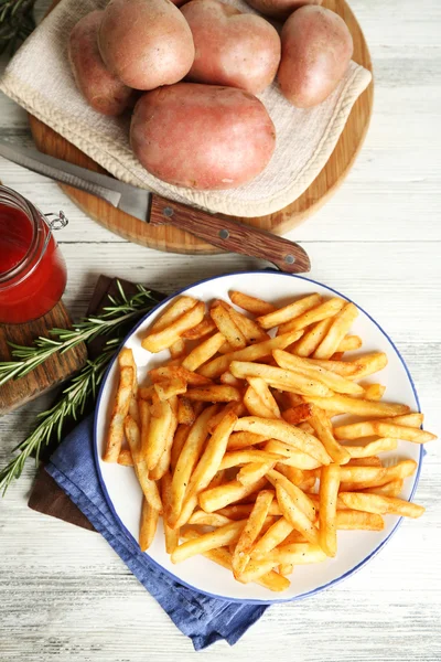 Tasty french fries on plate, on wooden table background — Stock Photo, Image