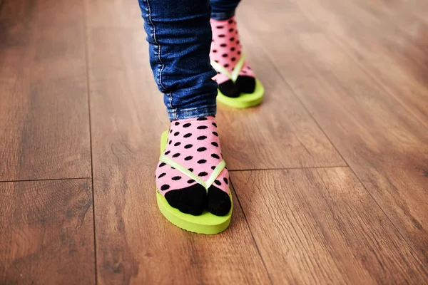 Ženské nohy v ponožkách s růžové žabky, na podlaze pozadí — Stock fotografie
