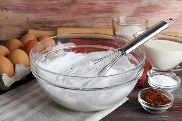 Šlehačka bílků a další ingredience na krém na dřevěný stůl, záběr — Stock fotografie
