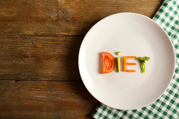 Word DIET made of sliced vegetables in white plate with napkin on wooden background — Stock Photo, Image