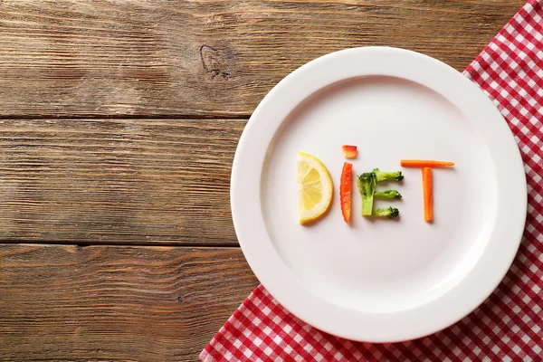 Word DIET made of sliced vegetables in white plate on wooden background — Stock Photo, Image