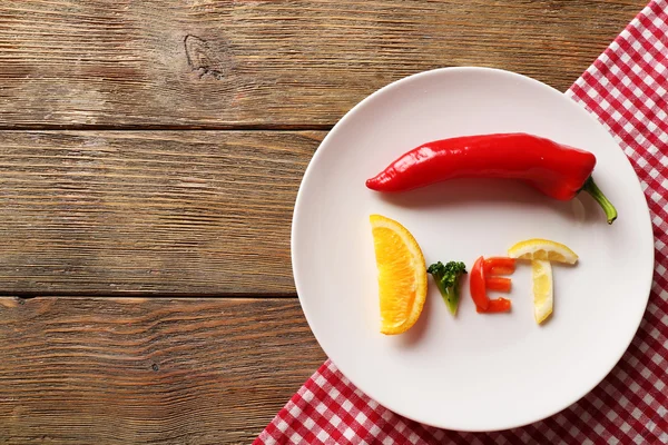 Word DIET made of sliced vegetables in white plate on wooden table, top view — Stock Photo, Image