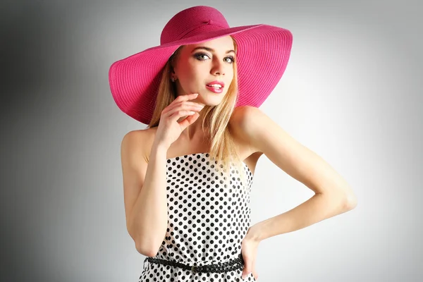 Modello giovane espressivo in cappello rosa su sfondo grigio — Foto Stock