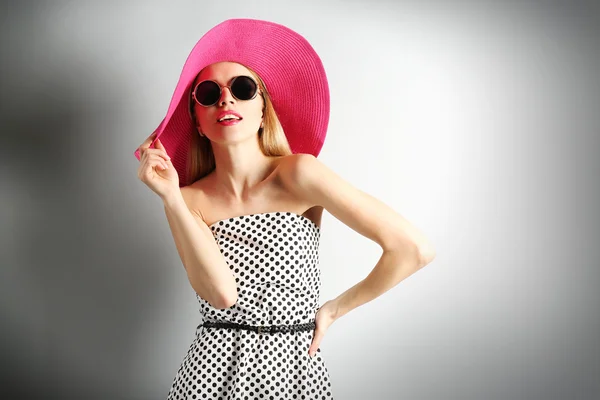 Expressive young model in pink hat with sunglasses on gray background — Stock Photo, Image