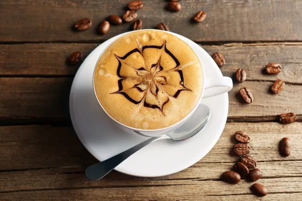 Xícara de café arte latte com grãos em fundo de madeira — Fotografia de Stock