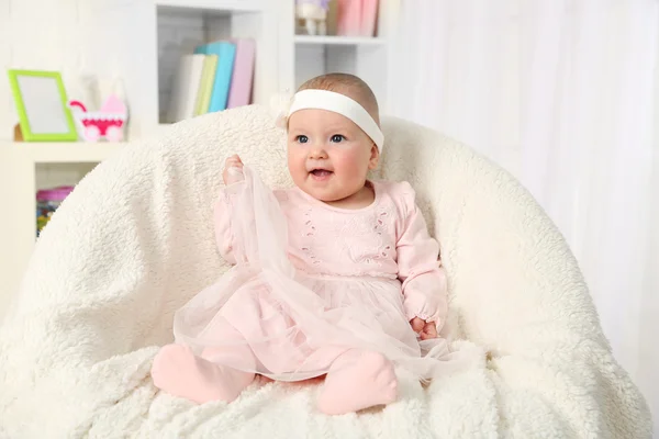 Menina bonito em vestido rosa sentado em cadeira de braço, em casa fundo interior — Fotografia de Stock