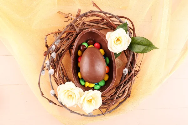 Chocolate Easter eggs with flowers in wicker nest, closeup — Stock Photo, Image