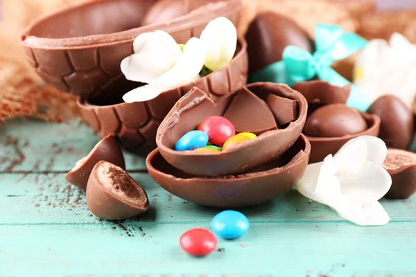 Schokoladen-Ostereier mit Blumen auf Holztisch, Nahaufnahme — Stockfoto