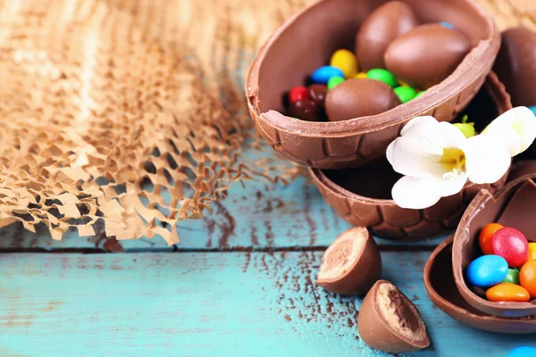 Suklaa pääsiäismunia kukkia puinen pöytä, lähikuva — kuvapankkivalokuva