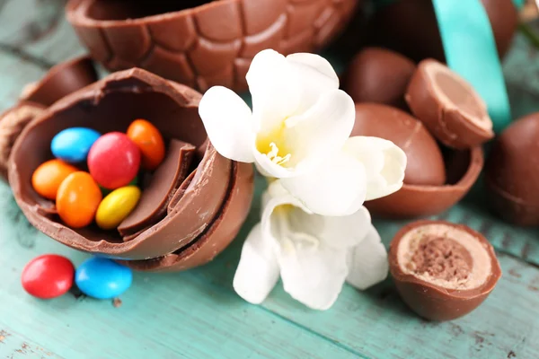 Ovos de Páscoa de chocolate com flores na mesa de madeira, close-up — Fotografia de Stock