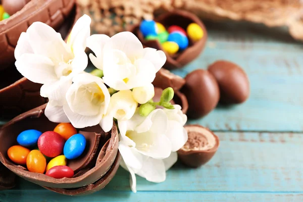 Ovos de Páscoa de chocolate com flores na mesa de madeira, close-up — Fotografia de Stock