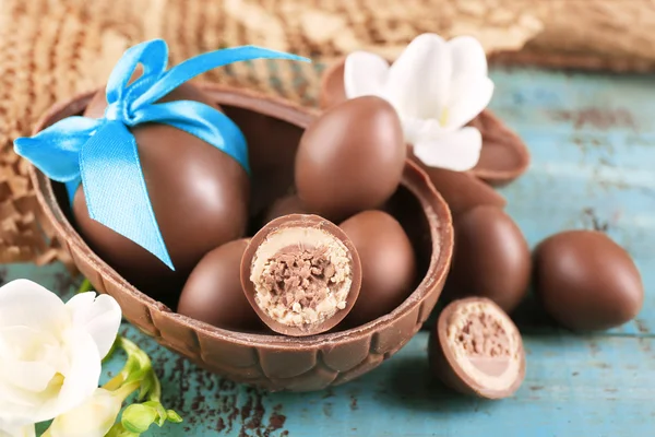 Chocolate Easter eggs with flowers on wooden table, closeup — Stock Photo, Image