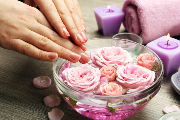 Mãos femininas com tigela de água de spa de aroma em mesa de madeira, close-up — Fotografia de Stock