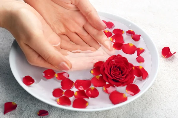 Mãos femininas com tigela de água de spa de aroma na mesa, close-up — Fotografia de Stock