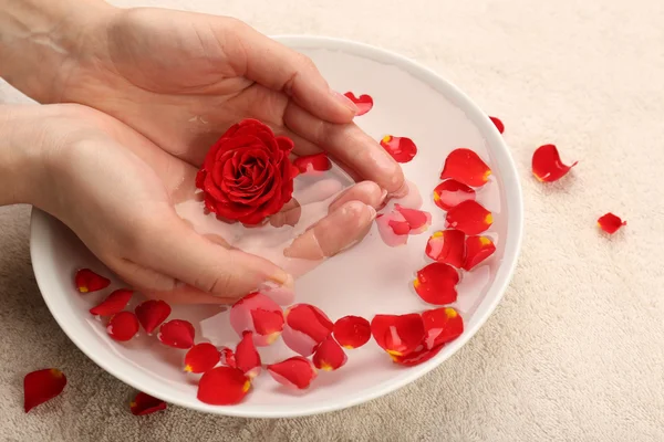 Mãos femininas com tigela de água de spa de aroma na mesa, close-up — Fotografia de Stock