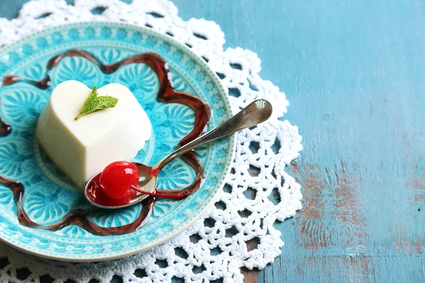 Smakelijke panna cotta dessert op bord, op houten tafel — Stockfoto