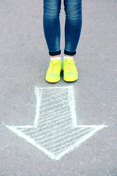 Női láb és a rajz nyíl a járdán háttér — Stock Fotó