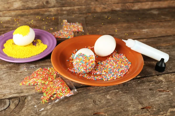 Decoración de huevos de Pascua en plato de color en la mesa de madera, primer plano — Foto de Stock