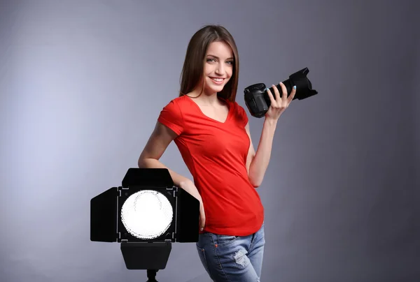 Jonge vrouwelijke fotograaf foto's nemen op grijze achtergrond — Stockfoto